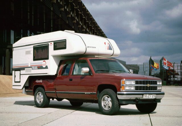 1990_Rote Tischer-Kabine auf GMC Pickup – unter Brücke geparkt, Seitenansicht.