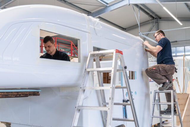 Tischer Wohnkabine Manufaktur– Mitarbeiter führt Detailarbeiten an Fensteröffnung durch.