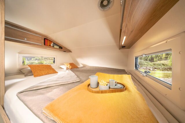 Alkovenbett der Tischer 260SP Flatbed mit Dachfenster und Tagesdecke in Ockergelb.