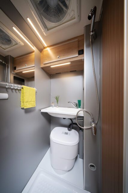 Duschbad mit WC, Waschbecken und beleuchtetem Spiegel in der MAN TGE Boxkabine.