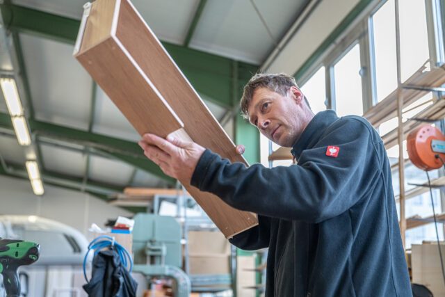 Qualitätskontrolle in der Tischer Schreinerei: Ein Mitarbeiter prüft sorgfältig eine frisch gefertigte Schublade.