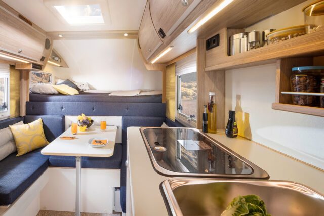 Blick in die Trail Box 220 mit Esstisch, Küchenblock und Schlafbereich im Alkoven.