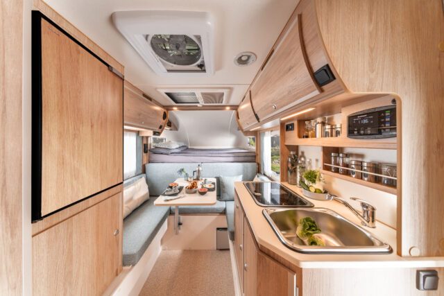 Innenansicht der Tischer 230S mit Sitzgruppe, Küche und Alkovenbett – kompakter Grundriss.