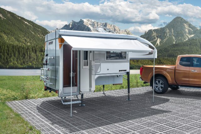 Aufgestellte Tischer Kabine auf Stellplatz mit Pick-Up als Basisfahrzeug. Halb ausgefahrene Markise