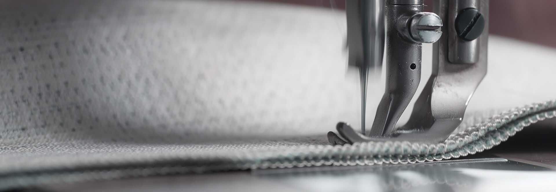 Detailaufnahme einer Nähmaschine beim Verarbeiten eines Stoffes – Symbol für Handarbeit und Präzision.