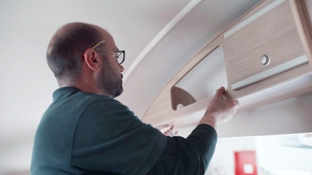 tischer_manufaktur_Mitarbeiter bei der Montage eines Wandteils im Kabineninneren.