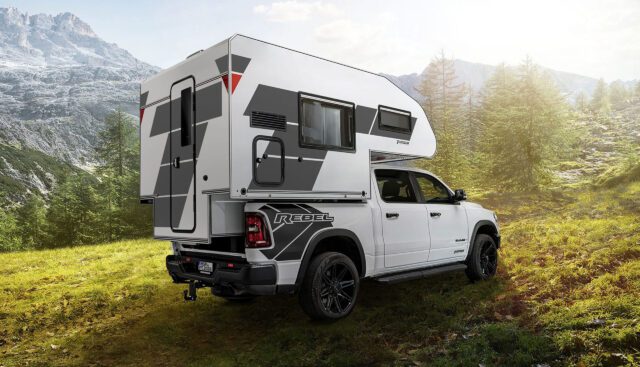 Weißer RAM Rebel Pickup mit Tischer-Wohnkabine BOX 200 Super Light auf einer Bergwiese.